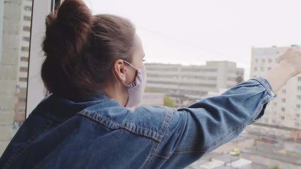 Young Woman in Face Mask Screaming Out Window alt