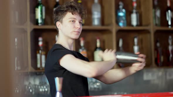 Confident Young Caucasian Bartender Shaking Cocktail Shaker in Bar Preparing Alcohol Beverage in alt