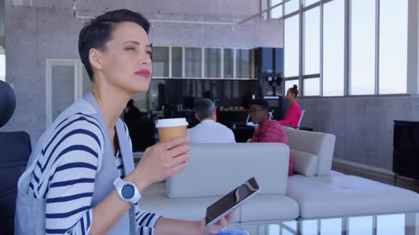 Beautiful Caucasian Businesswoman using digital tablet while drinking coffee in modern office 4k alt