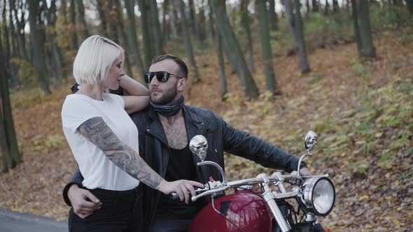 Portrait of Lovely Couple Stands in Pose Looks on Each Other and Aside alt