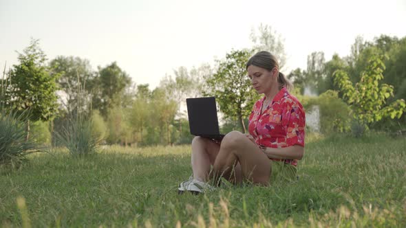 A Middleaged Woman Works Using Her Laptop in a Public Park