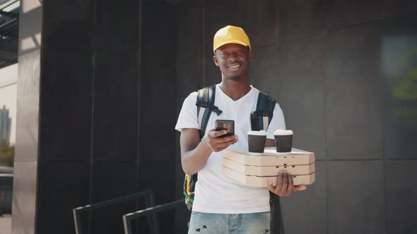 Portrait of African Courier with Package and Smartphone Carrying Box of Pizza alt