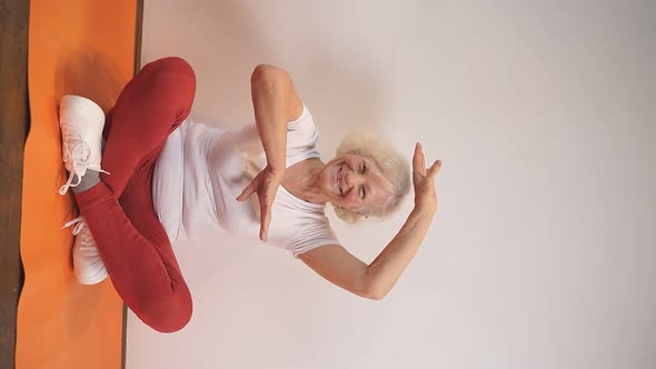 Active Positive Elderly Woman Doing Yoga on the Carpet at Home