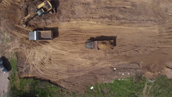 Aerial top view: loaded tipper with soil moving reverse to pour out ground
