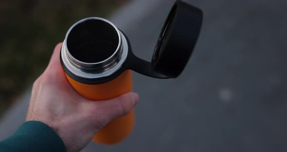 POV Male Hand Holding Thermos with Hot Tea in It alt