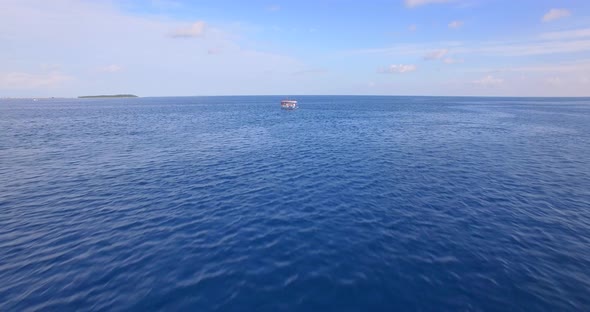 Aerial drone view of a motor boat going to a scenic tropical island in the Maldives. alt