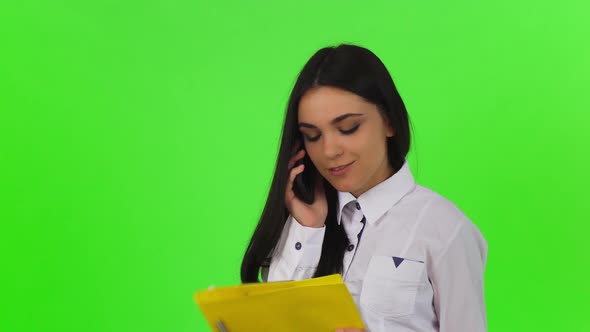 Attractive Businesswoman Talking on the Phone, Holding Clipboard alt