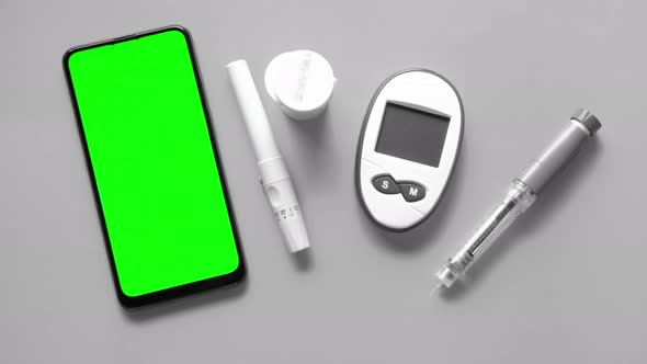 Smart Phone Green Screen, insulin pen and diabetic measurement tools on table