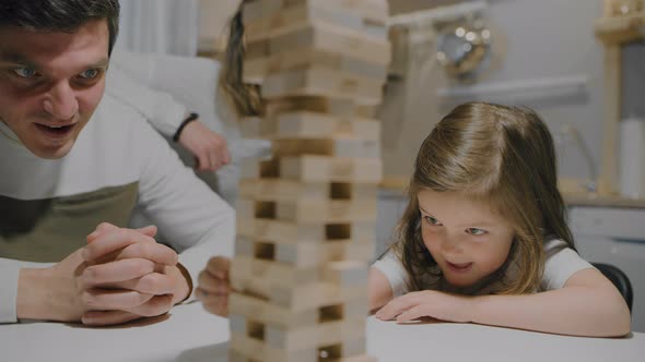 Father and Daughter are Playing a Board Game Made of Wooden Blocks