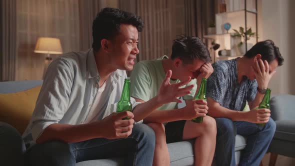 Three Asian Males Cheering And Watching Football Game On Tv And Disappointed At Home alt