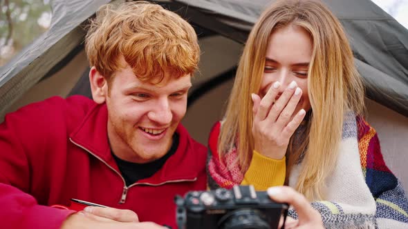 Young Couple Laughing Looking at Camera and Discussing Funny Photos alt