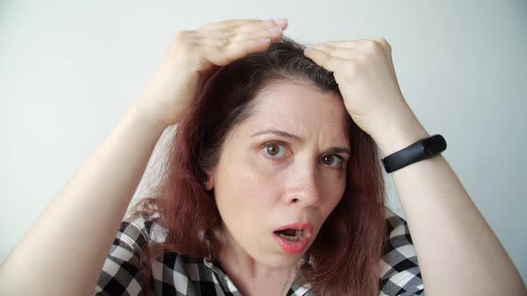 Young Frustrated Woman Looks in the Mirror and Plucks a Grey Hair From Her Head. Concept Photo of alt