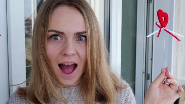 Portrait of Beautiful Blonde Happy Woman Holding Symbol Heart alt