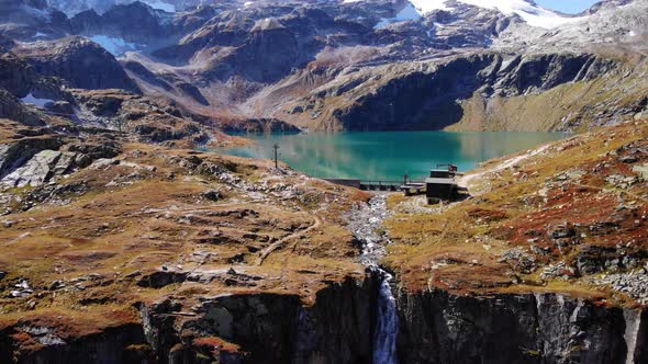 Aerial View Of Waterfall Flowing Into Mountain Cliff From Weisssee Reservoir Spillway In Austria. alt