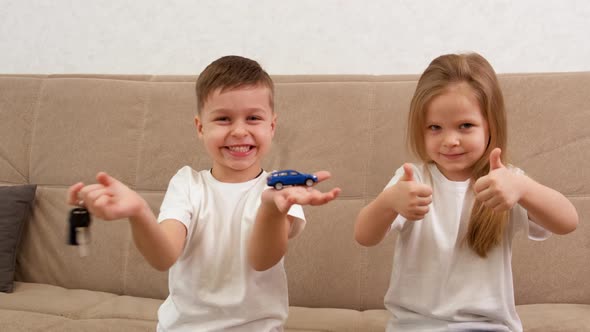 A Boy Holds a Toy Car and Keys and Smiles Biggest alt
