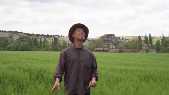 A Worried Middleaged Farmer Looks Up at the Sky in Anticipation of Rain alt