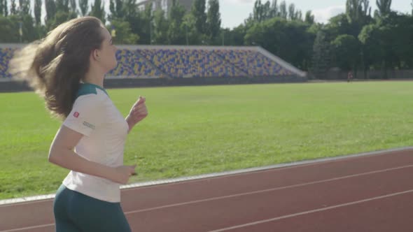 Athletic Young Girl Runs in the Stadium. Slow Motion alt