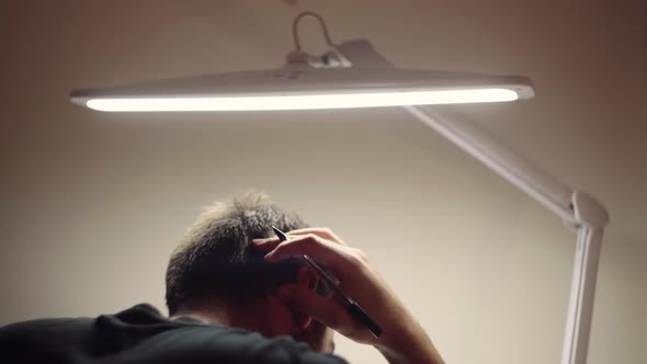 Bearded Man Scratched The Back Of His Head While Studying At Night. - over the shoulder shot alt