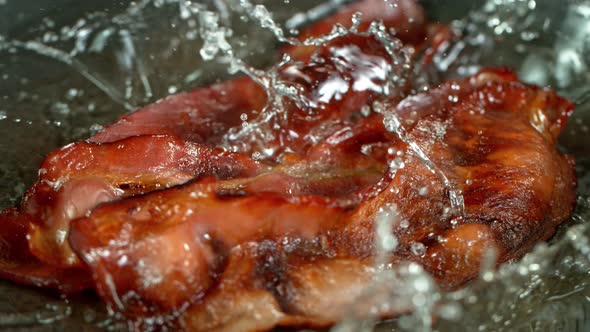 Super Slow Motion Shot of Roasted Bacon Slices Falling Into Pan at 1000 Fps. alt