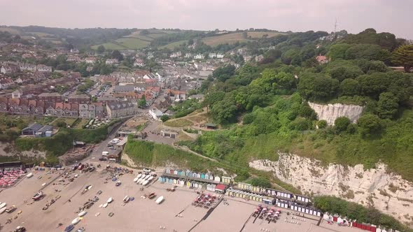 Aerial shot flying away from the Devon coastline with beautiful cliffs and buildings on the coast alt
