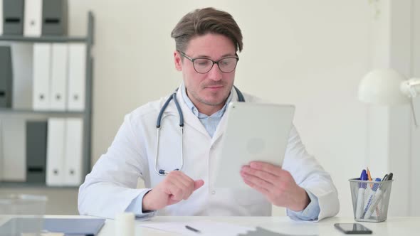 Video Call on Tablet By Middle Aged Male Doctor alt