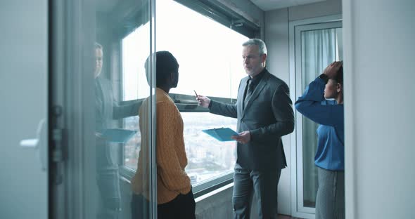 Mature real estate agent showing apartment to multi ethnic young couple alt
