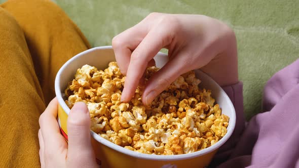 Close Up View on Female Hand Holding a Popcorn While Watching a Movie in the Living Room alt