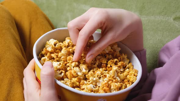 Close Up View on Female Hand Holding a Popcorn While Watching a Movie in the Living Room