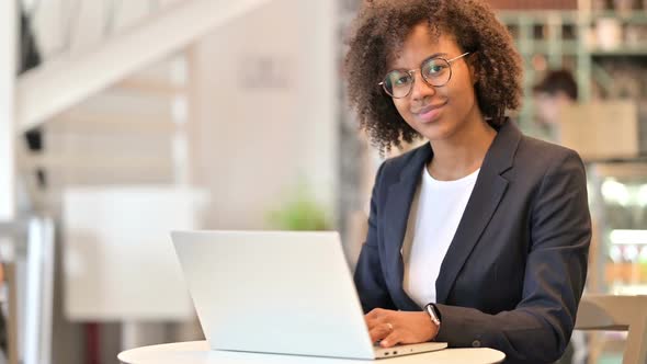 Young African Businesswoman with Laptop Smiling at Camera in Cafe alt