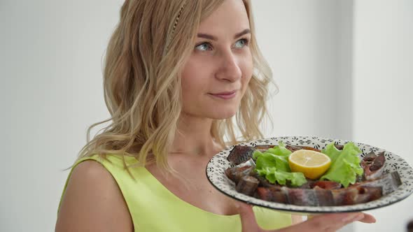 Healthy Food Smiling Woman Sniffing Aroma of Delicious Fish Cut Into Pieces and Laid Out on Plate alt