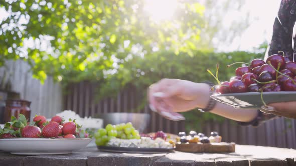 Girl Puts Plates with Tasty Strawberries Cherries on Table