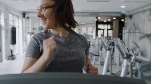 Handheld view of young women running on the treadmill at gym.  Shot with RED helium camera in 8K alt
