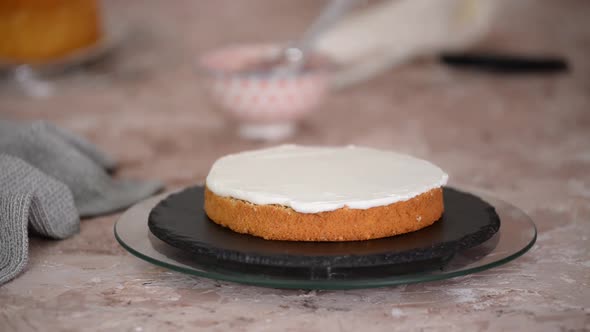 A woman spreads cream on top of the cake layers.