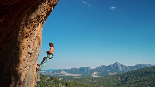 Side View of Strong Attractive Man Rock Climber Getting Ready to Descend From Vertical Cliff on Top alt