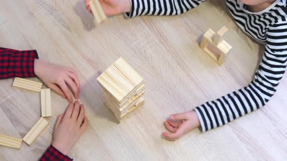 Children Playing Wooden Block Removal Tower Game at Home alt