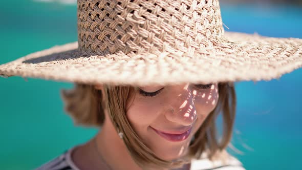 Pretty Woman in Straw Hat Smiling Sincerely on Blue Sea Background