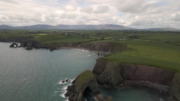 Drone shot showing of a large landscape in Ireland with a beach and sea cliffs. alt