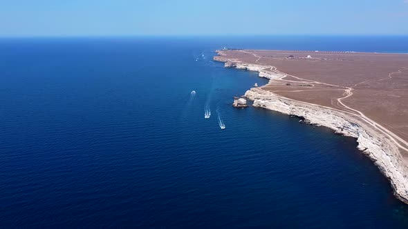 Endless Blue Sea with Floating Boats on a Calm Sea Near the Rocks Steep Shore Bird's Eye View