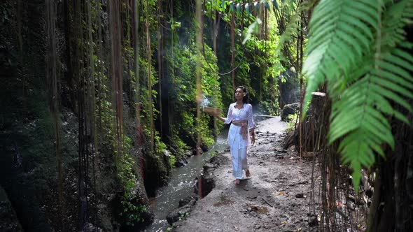 Divine Woman Walking in the Tropical Jungle Along the Brook Meditating Contemplation Burning alt