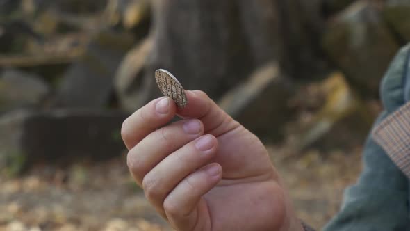 Man Holding a Coin and Defocused Shot of Jungle That Surrounds Cambodian Temple alt