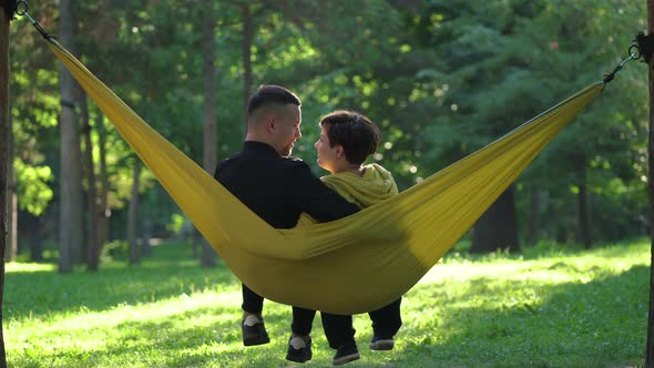 Couple sitting in a hammock and talking alt