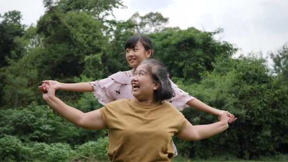 Slow motion of Happy grandmother with granddaughter playing in the park