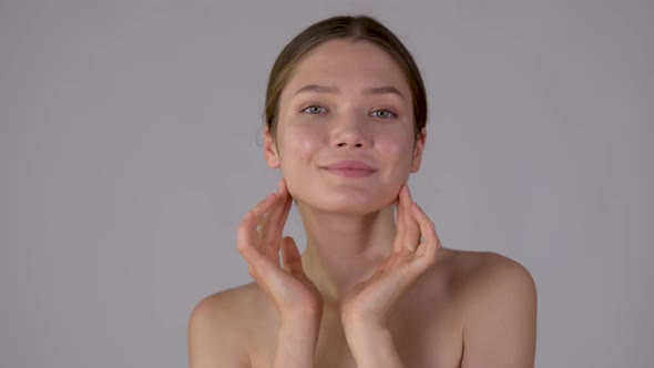 Attractive smiling woman touch face after applying cream remove makeup look at camera alt