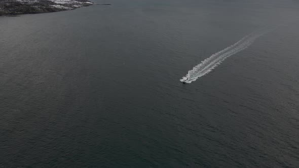 Drone tracking boat cruising along Arctic waters, high angle view alt