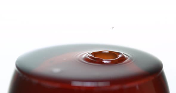 Drop of Red Wine being poured into Glass, against White Background, Slow motion 4K