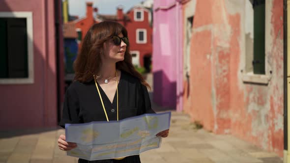 Real Time Portrait Shot of a Girl Walking with a Map on the Streets of Burano.