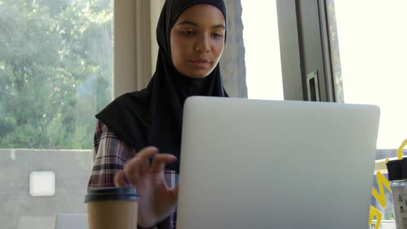 Young woman using laptop in a cafe alt