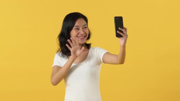 Happy Asian woman video calling and sending a kiss with the smart phone in Portrait studio