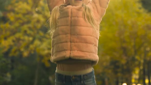 Cute Girl in Fur Coat Throwing Up Autumn Leaves, Carefree and Happy Childhood alt