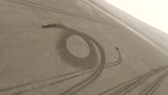 Aerial Rotation Shot Two Extreme Buggy Car Racing on Sandy Desert Surrounded By Dust and Smog alt